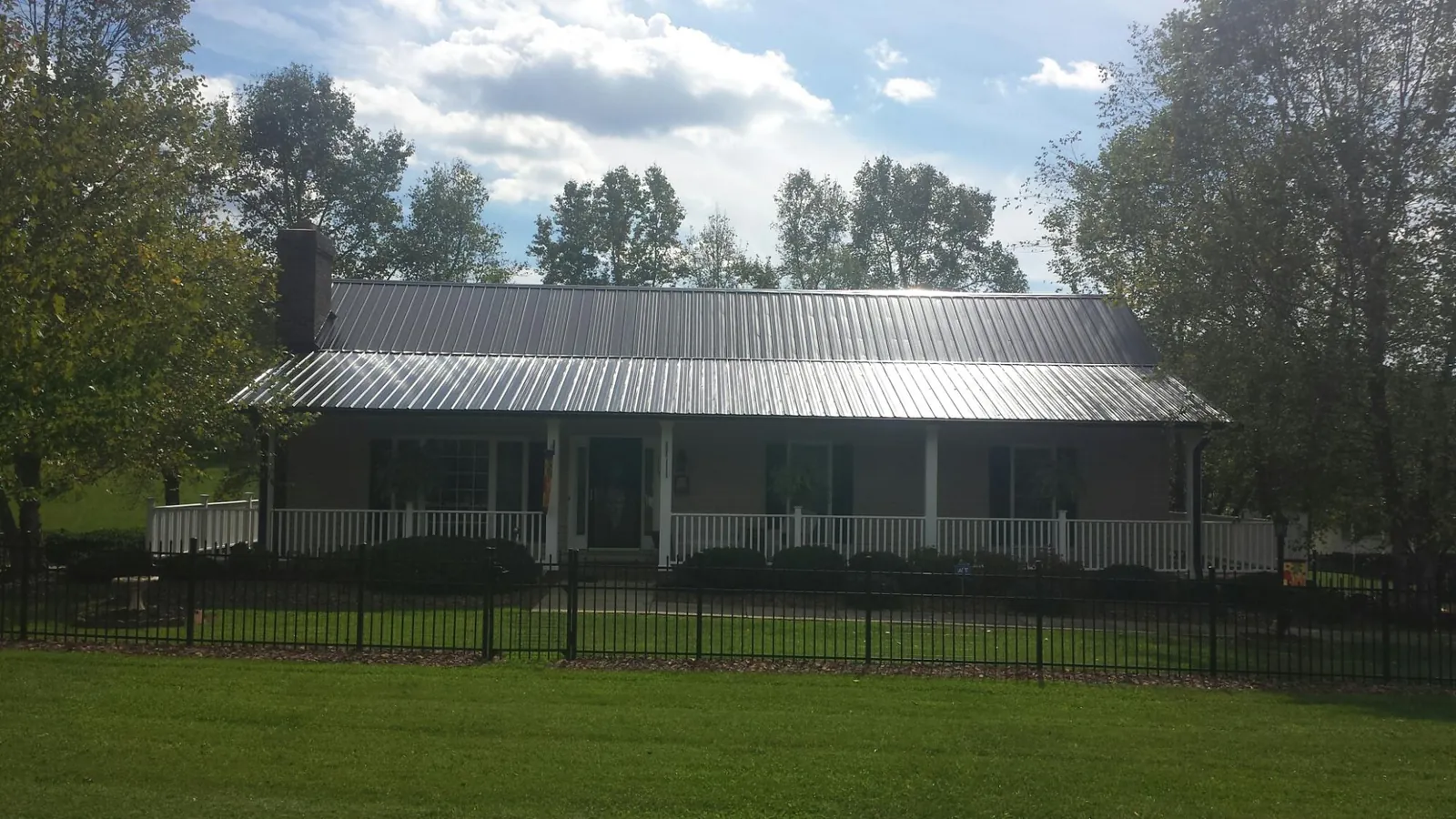 Gray metal roof on a brick ranch with a full width front porch — Gutter Guard Installation work by our crew in Luzerne