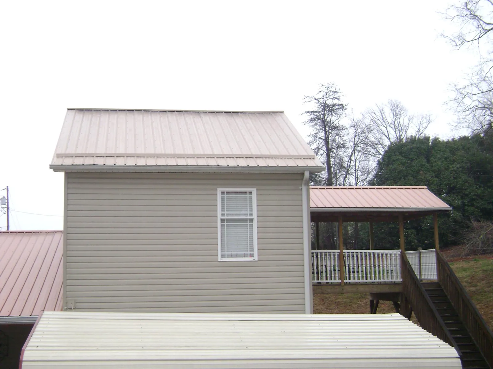 Tan metal roofs on a two story addition and attached porch, from a Roof Replacement job in Luzerne