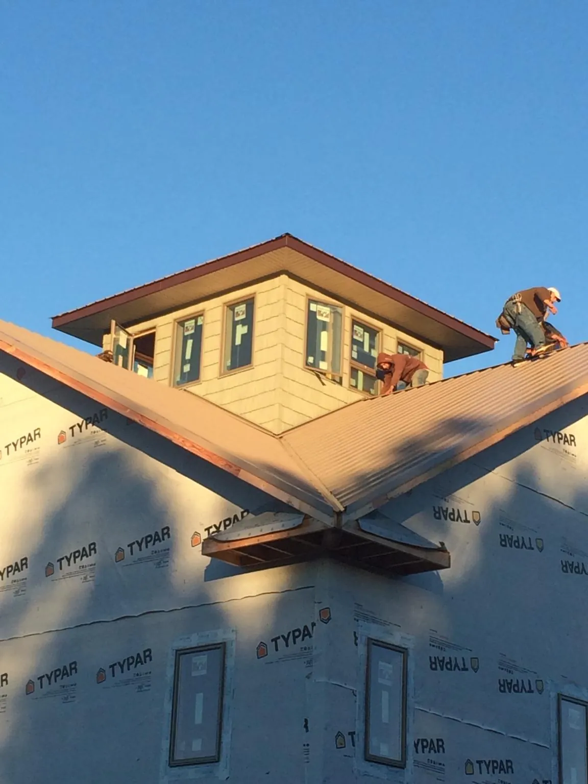 Roofers working around a rooftop cupola on a new metal roof at sunset — Roof Waterproofing in Luzerne by Roofing Brothers